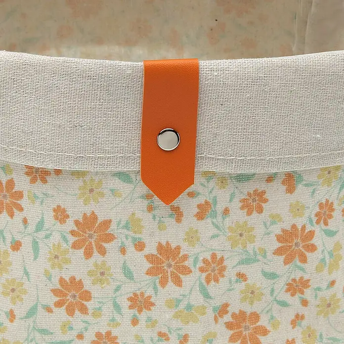 Versa Juego de cestas - Flores naranja, 3 ud. - Primer plano de una cesta de tela con un estampado floral y un cierre naranja.