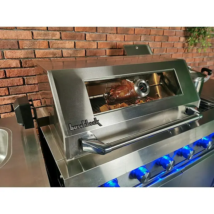 Buschbeck Outdoorküche Oxford - Edelstahl, Anzahl Brenner: 4 - Buschbeck Grill mit Rotisserie, auf dem ein köstliches Gericht zubereitet wird. Die blauen Bedienelemente verleihen dem Grill einen modernen Touch.