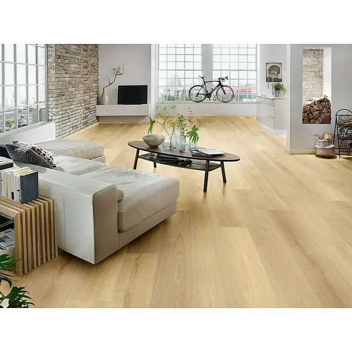 Krono Original Laminat Organic Clever Long Silent - Farrow Montreux Oak, Landhausdiele, 2.003 x 245 x 7 mm - Ein helles Wohnzimmer mit einem beigen Ledersofa und einem ovalen Couchtisch auf einem hellen Holzboden. Die Einrichtung ist modern und einladend.