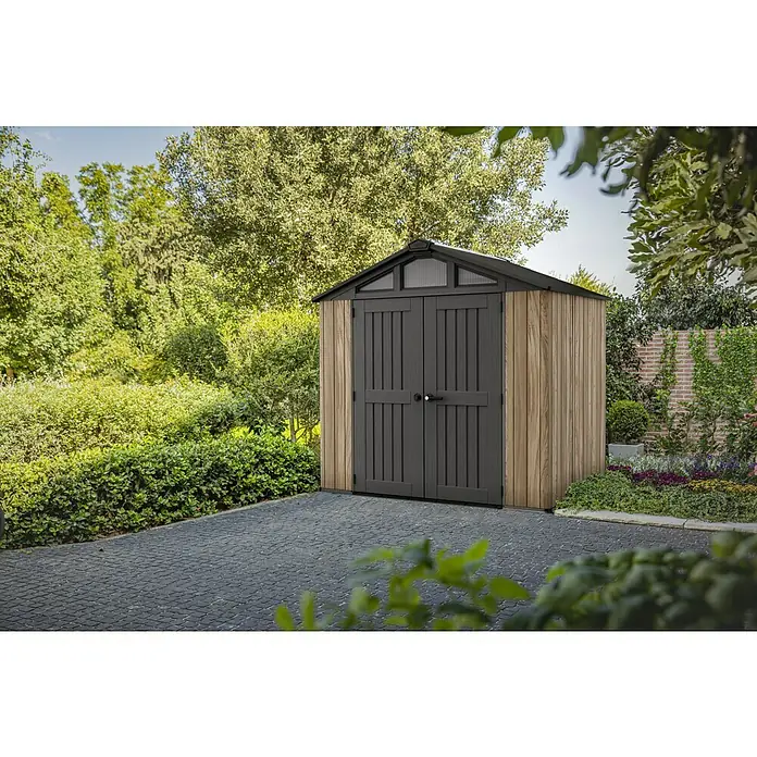 Keter Gerätehaus Stronghold 8x6 - Außenmaß inkl. Dachüberstand (B x T): 248,5 x 248,5 cm, Kunststoff, Eiche/Schwarz - Gartenszene mit einem geräumigen Holzschuppen mit dunklen Türen und einem transparenten Oberlicht, der sich perfekt in jeden Garten einfügt.