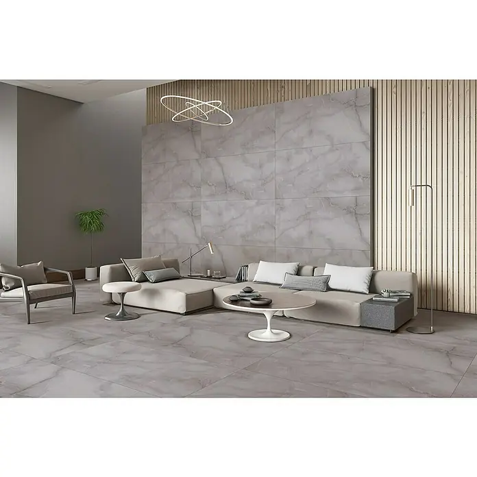 Feinsteinzeugfliese Royal Onyx - 60 x 120 cm, Dark Grey, Glänzend - Ein modernes Wohnzimmer mit einem großen Sofa, einem Couchtisch und einem eleganten Sessel. Die grauen Fliesen unterstreichen das stilvolle Ambiente.