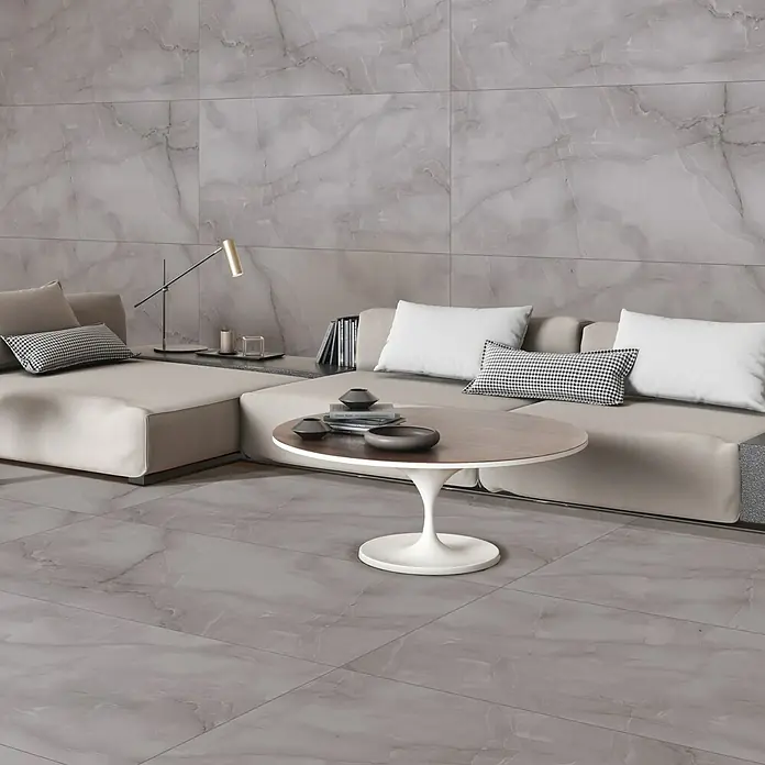 Feinsteinzeugfliese Royal Onyx - 60 x 120 cm, Dark Grey, Glänzend - Elegantes Wohnzimmer mit grauem Marmorboden und passender Wandverkleidung, ergänzt durch ein modernes Sofa und einen stilvollen Couchtisch.