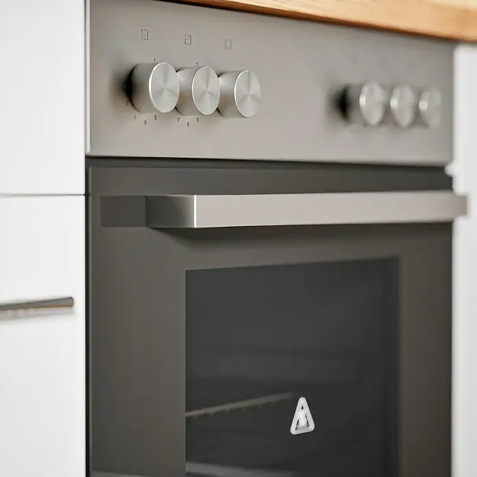 Respekta Composición de cocina Hilde - Ancho: 280 cm, Blanco, Con electrodomésticos - Primer plano de un horno moderno con manijas y perillas de acero inoxidable en una cocina luminosa.