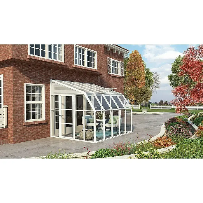 Palram – Canopia Terraza Solarium Sun Room - Medidas ext. (An x Pr): 322 x 257 cm, Plástico, Blanco - Una elegante terraza acristalada blanca adosada a una casa de ladrillo, amueblada de forma acogedora con sillas y una mesa.