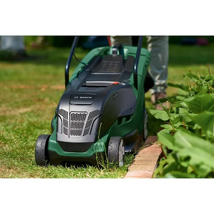 Bosch Elektro-Rasenmäher UniversalRotak 450 - Leistung: 1.300 W, Schnittbreite: 34 cm - Nahaufnahme eines grünen Bosch Rasenmähers auf einem Rasen, der an einem sonnigen Tag ein gepflegtes Finish erzielt.