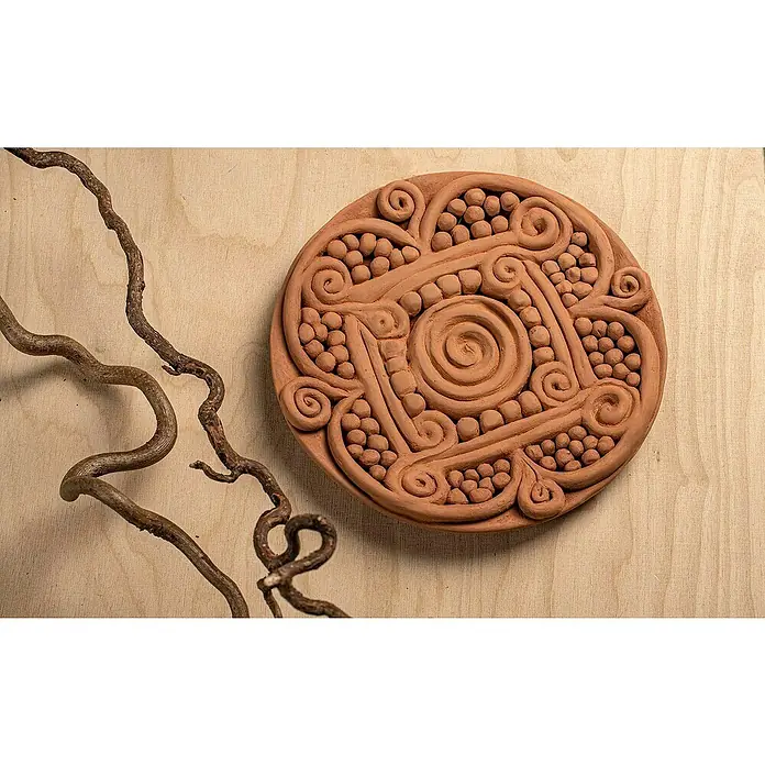 Glorex Hobby Time Softton - 500 g, Terracotta - Ein handgefertigtes rundes Terrakotta-Kunstwerk mit komplizierten Spiralen und Punktmustern, neben einem dekorativen Zweig auf einem Holzgrund.