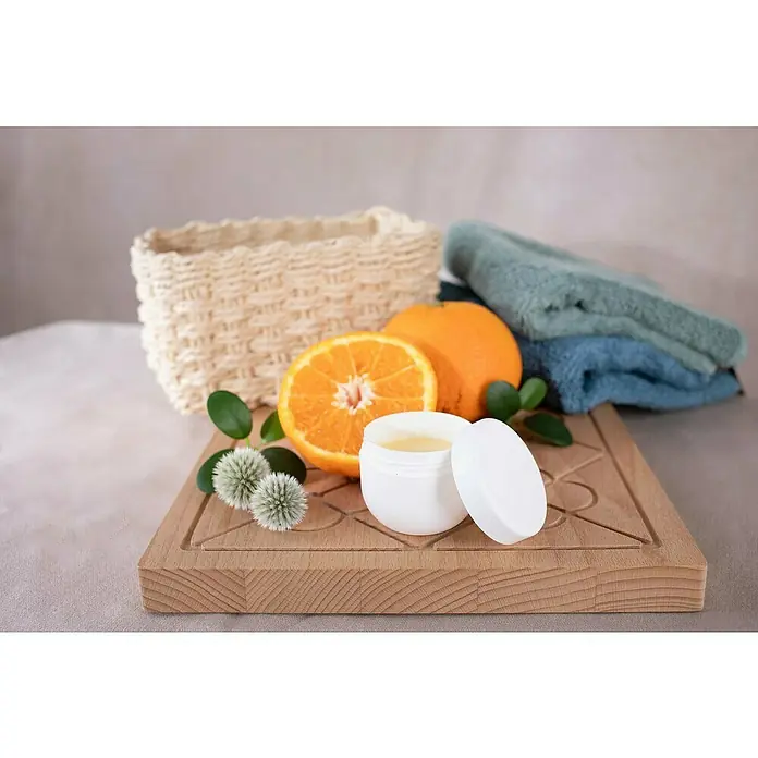 Glorex Bastel-Set Natur-Kosmetik Handcreme - 8 -tlg. - Hautpflegeprodukt mit Orange, präsentiert mit einem Korb, Handtüchern und Blüten auf einem Holzbrett. Ideal für die tägliche Hautpflege.