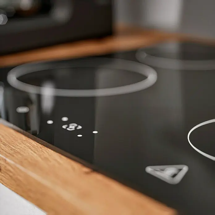 Respekta Cocina compacta Hilde - Ancho: 220 cm, Gris, Se pueden montar de forma intercambiable, Con electrodomésticos - Primer plano de una moderna placa de cocción negra con panel de control y marcas de la zona de cocción sobre una encimera de madera.