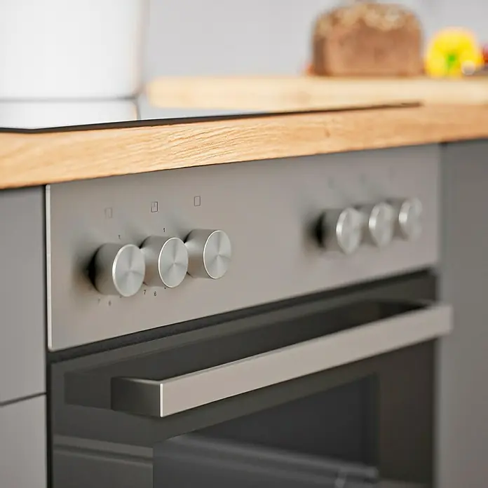Respekta Cocina compacta Hilde - Ancho: 220 cm, Gris, Se pueden montar de forma intercambiable, Con electrodomésticos - Primer plano de un horno plateado moderno con mandos giratorios y un asa horizontal, integrado en un mueble de cocina gris.
