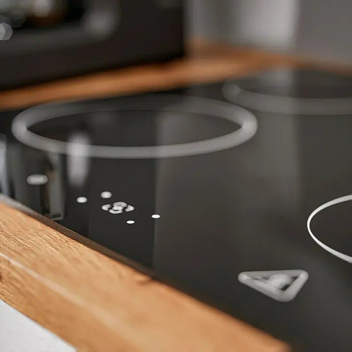 Respekta Cocina compacta Hilde - Ancho: 220 cm, Blanco, Se pueden montar de forma intercambiable, Con electrodomésticos - Primer plano de una placa de inducción negra con borde de madera, que enfatiza los diseños de cocina modernos y resalta los paneles de control.