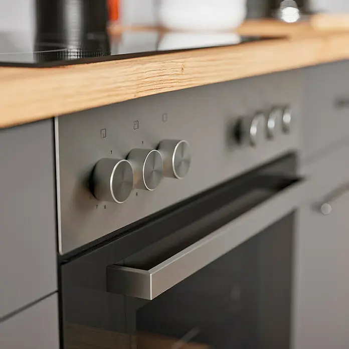 Respekta Cocina esquinera Hilde - Ancho: 250 cm, Gris, Mate, Efecto madera, Con electrodomésticos - Primer plano de un horno gris moderno con controles y asa plateados en un entorno de cocina de madera clara.