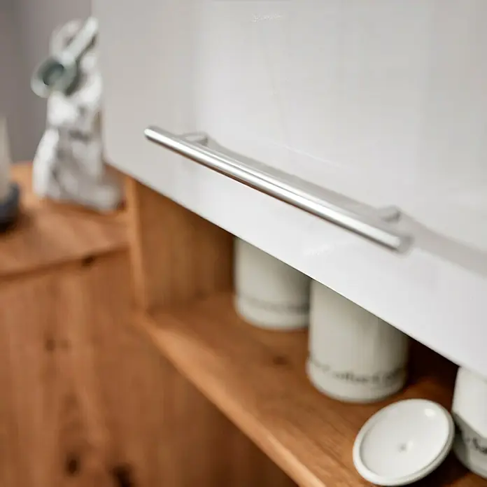 Respekta Cocina esquinera Hilde - Ancho: 250 cm, Blanco, Mate, Efecto madera, Con electrodomésticos - Imagen detallada de un armario de cocina blanco con un mango largo plateado, debajo del cual hay un estante de madera abierto con recipientes blancos.