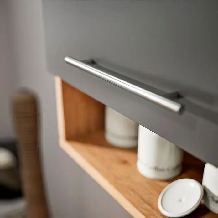 Respekta Cocina esquinera Hilde - Ancho: 280 cm, Gris, Mate, Efecto madera, Con electrodomésticos - Primer plano de un armario de baño gris con tirador plateado y estante abierto de madera, mostrando una elegante organización del baño.