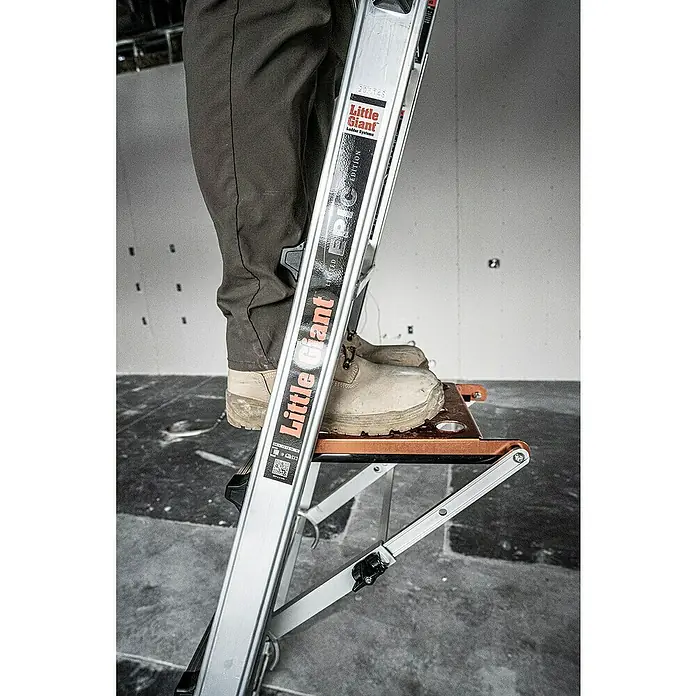 Little Giant Trittablage Platform Pro® - Belastbarkeit: 150 kg - Nahaufnahme einer Little Giant Leiter, auf der eine Person steht, die ihre Vielseitigkeit und Robustheit hervorhebt.