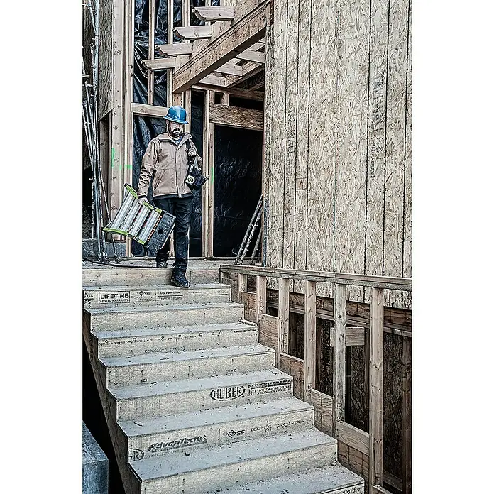 Little Giant Mehrzweckleiter 6+4 STUFEN - Anzahl Tritte: 10 Stk., Arbeitshöhe: 3,99 m, Verbundwerkstoff - Mann mit Schutzhelm auf einer Baustelle, der eine Treppe mit Stufen aus Huber AdvanTech Bauplatten hinuntergeht und eine Leiter trägt.