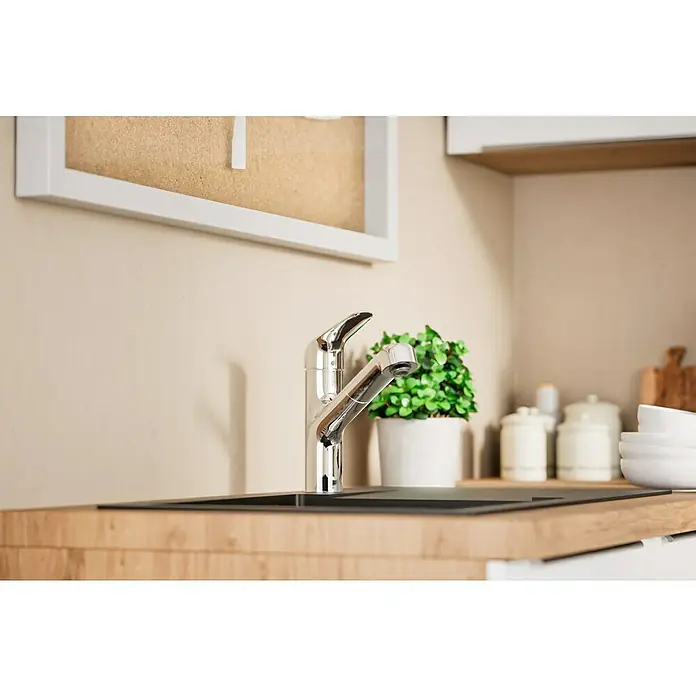 Hansgrohe Focus M41 Grifo de cocina - Cromo, Brillante - Primer plano de un moderno grifo de cocina cromado con un fregadero, una planta y botes al fondo.