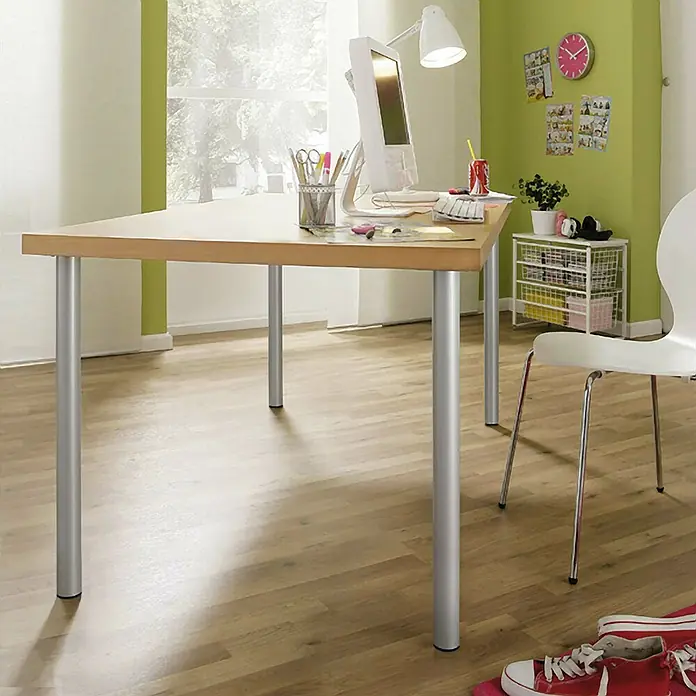 Pata para muebles - Ø x Al: 6 x 71,5 cm, Acero, Níquel - Un escritorio luminoso con patas plateadas se encuentra en una habitación con pisos de madera. Una computadora y varios artículos de oficina están en la mesa.