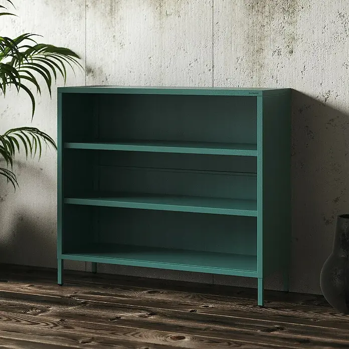 Jan Nowak Bücherregal Luca - B x T x H: 100 x 35 x 90 cm, Meeresgrün - Ein grünes Bücherregal mit drei Regalen, das vor einer Betonwand und neben einer Zimmerpflanze steht.