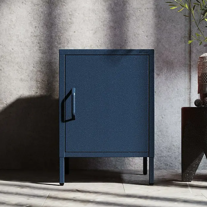 Jan Nowak Nachttisch Mia - L x B x H: 40 x 42,4 x 59,5 cm, Dunkelblau - Ein blauer Metallschrank mit einer Tür und einem Griff steht auf einem gefliesten Boden vor einer grauen Wand.
