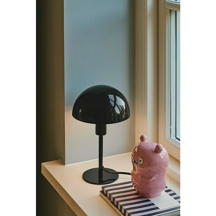 Nordlux Lámpara de sobremesa Ellen mini - 40 W, L x An x Al: 16 x 16 x 25 cm, Negro, E14 - Elegante lámpara de escritorio negra con diseño de hongo colocada en un alféizar junto a un juguete rosa y un libro.