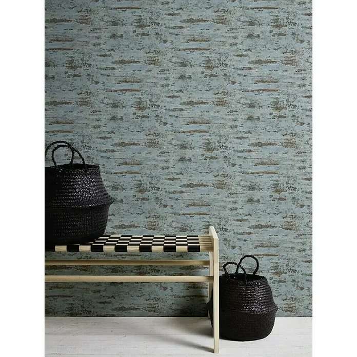 A.S. Création Neue Bude 2.0 ED II Vliestapete Used Ziegel - Blau/Braun/Grau, Steinoptik, 10,05 x 0,53 m - Zwei schwarze Körbe und eine helle Holzbank mit Schachbrettmuster-Sitzband vor einer strukturierten blau-braunen Wand.