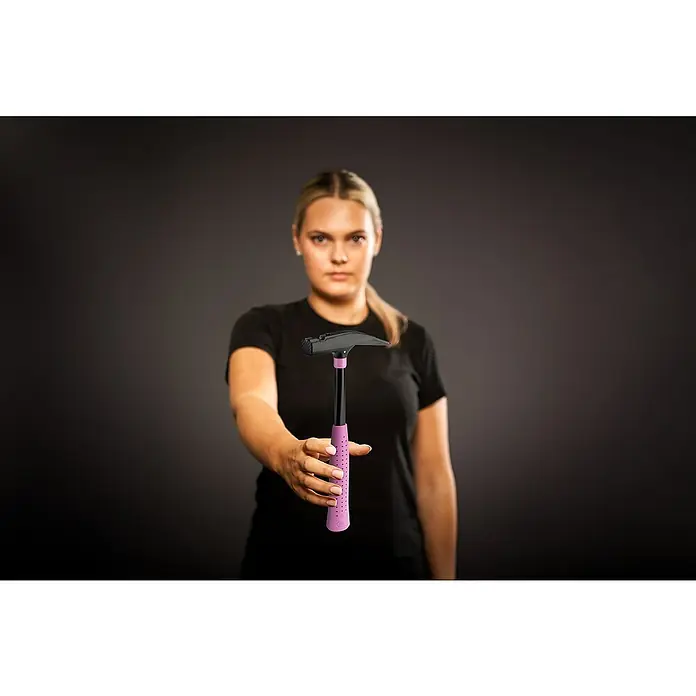 Picard Zimmermannshammer - Gewicht Kopf: 600 g, Pink - Frau hält einen Hammer mit violettem Griff in die Kamera. Das Werkzeug ist das Hauptmotiv vor einem dunklen Hintergrund.