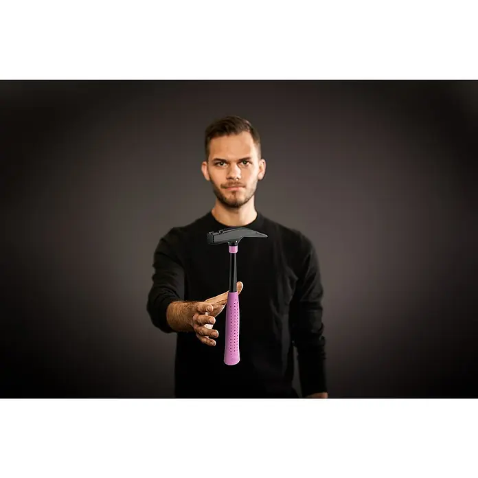 Picard Zimmermannshammer - Gewicht Kopf: 600 g, Pink - Nahaufnahme eines Mannes, der einen Hammer mit rosafarbenem Griff vor einem dunklen Hintergrund hält.