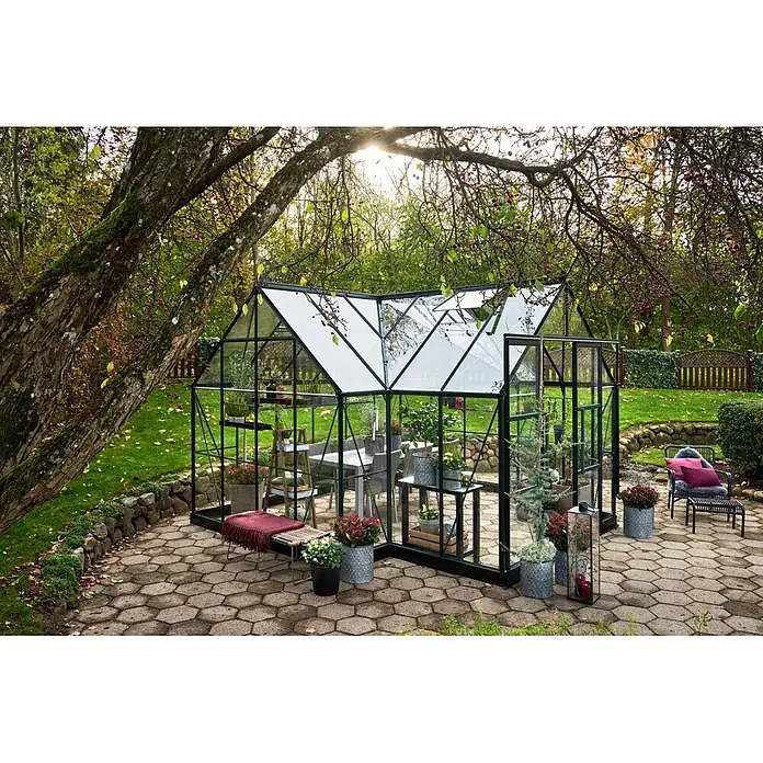 Halls Gewächshaus Garden Room - Außenmaß inkl. Dachüberstand (B x T): 389 x 390 cm, Farbe Gestell: Grün, Wandstärke: 3 mm - Schwarz gerahmtes Glasgewächshaus in einem üppigen Garten, ausgestattet mit Pflanzen und Sitzgelegenheiten.