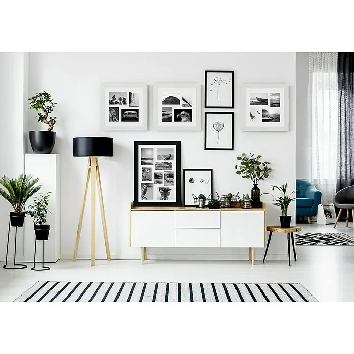 Marco de fotos Dalia - 24 x 30 cm, Negro, Vidrio - Un salón moderno con un aparador, marcos de fotos, plantas y una lámpara de pie. Los acentos en blanco y negro crean un contraste elegante.