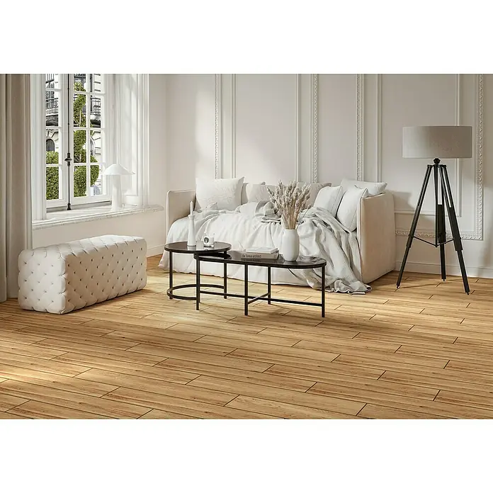 Steingutfliese Mini York - 60 x 11 cm, Sabbia, Matt - Elegantes Wohnzimmer mit stilvollem Sofa, Couchtisch und passendem Hocker auf einem warmen Holzboden. Die Lampe rundet das Ambiente ab.