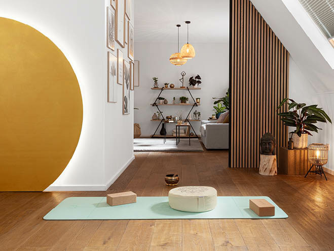 Aus einer Holzplatte wurde eine große Sonne an der Wand gestaltet und mit LED-Streifen hinterleuchtet, am Boden die Yoga-Matte