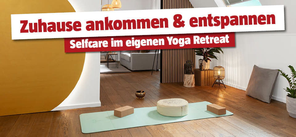 Yoga Matte am Boden mit Sitzblöcken und Sitzkissen, daneben Stehlampen und Pflanzen