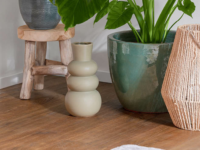 Brauner Parkettboden mit Vase, Übertopf und anderer Deko am Boden