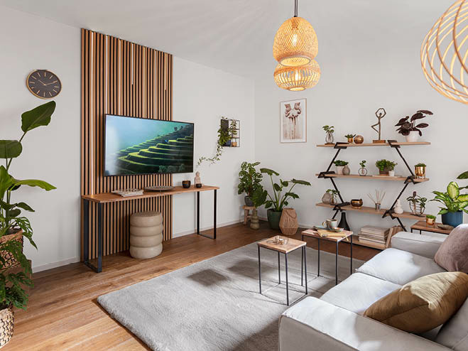Akustikpaneel mit LED-Streifen hinter dem TV, viele Naturmaterialien als Deko, Couch und Teppich in grau