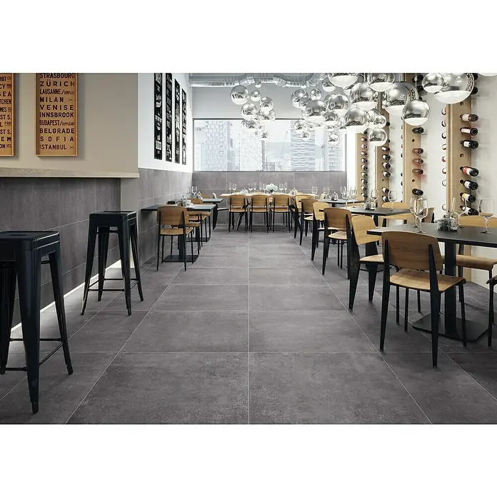 Feinsteinzeugfliese Savanna - 79,7 x 79,7 cm, Anthrazit, Matt - Elegantes Restaurant mit stilvollen grauen Fliesen, modernen Möbeln und raffiniertem Beleuchtungskonzept für ein ansprechendes Ambiente.