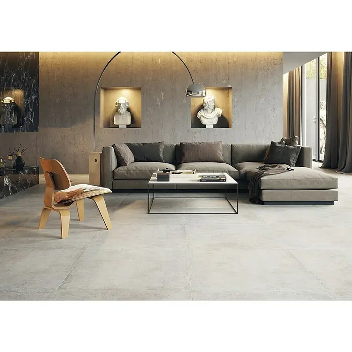Feinsteinzeugfliese Savanna - 59,7 x 59,7 cm, Gris, Matt - Ansicht eines hellen Wohnzimmers mit grauer Couch, modernem Couchtisch und einem stilvollen Holzstuhl auf hellem Fliesenboden.