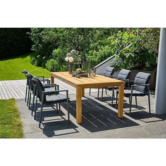 Sunfun Gartenmöbel-Set Laura/Solo Rope - 13 -tlg., Akazie, Aluminium, Olefin, Naturbraun/Night-Grey - Ein einladender Esstisch aus Holz mit grauen Stühlen auf einer Terrasse, umgeben von üppigem Grün, lädt zum Verweilen im Freien ein.