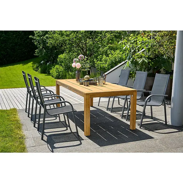Sunfun Gartenmöbel-Set Laura/Maja - 7 -tlg., Akazie, Aluminium, Textilen, Naturbraun/Night-Grey - Ein einladender Esstisch aus Holz mit stilvollen Stühlen auf einer Terrasse, umgeben von üppigem Grün. Ideal für Mahlzeiten im Freien.