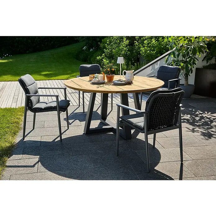 Sunfun Gartenmöbel-Set Solo Rope - 6 -tlg., Aluminium, Teak, Olefin, Grau, Natur - Ein runder Gartentisch aus Holz mit vier grauen Stühlen auf einer gepflasterten Terrasse, umgeben von Grün. Ideal für Mahlzeiten im Freien.