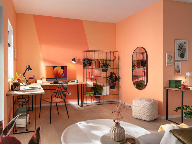 Wohnbereich mi Home Office, die Wände mit der Trendfarbe Peach Fuzz gestrichen und mit schwarzen Möbeln und Details bestückt