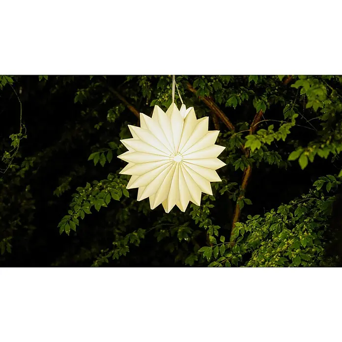 BAUHAUS Hängelampe Sonne - Durchmesser: 32 cm, Weiß, IP44 - Diese Aufnahme zeigt eine strahlende, sternförmige Papierlaterne, die an einem Baum hängt und warmes Licht in die Nacht wirft.