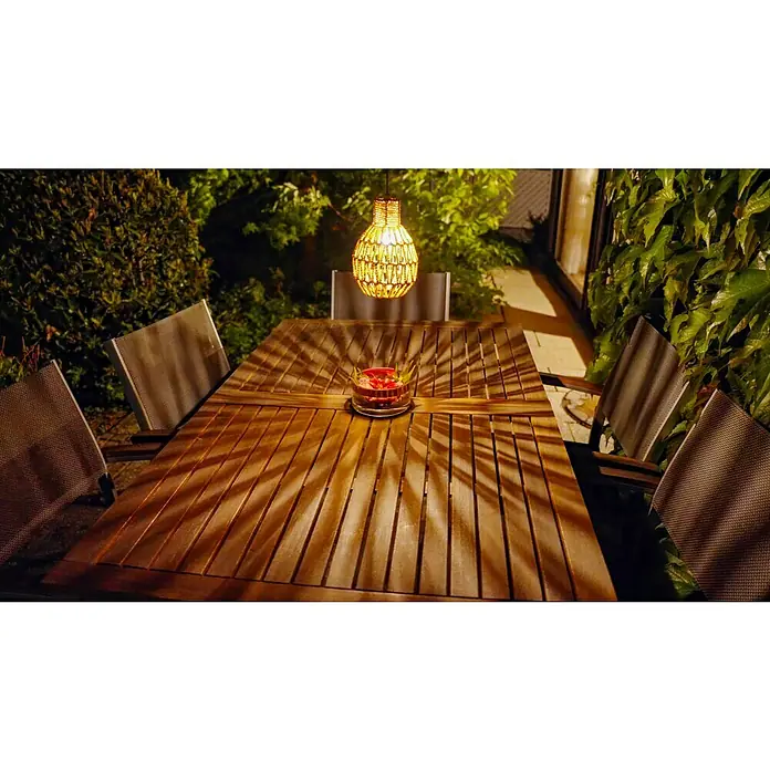 Starlux Hängelampe Rattan - B x L: 14,5 x 21,5 cm, Braun, IP44 - Stimmungsaufnahme eines rustikalen Holztisches mit einer dekorativen Lampe, die ein warmes Licht auf eine Schale mit roter Dekoration wirft.