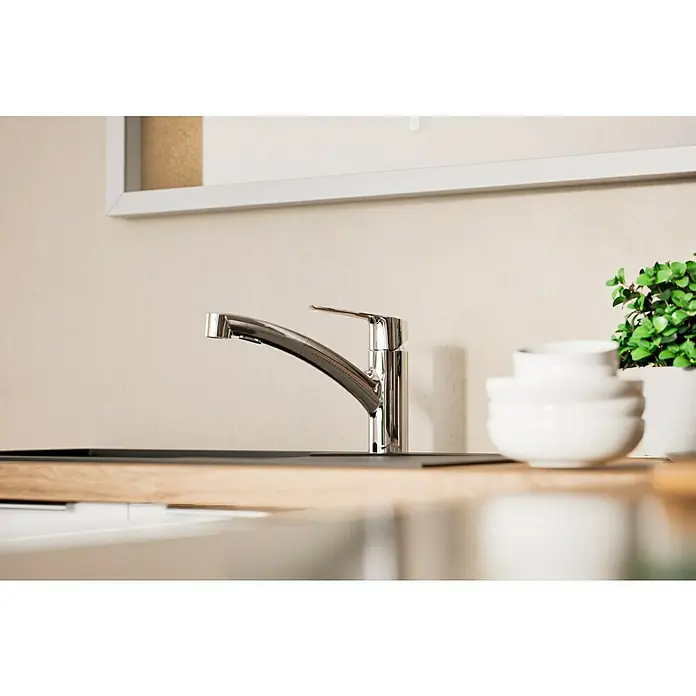 Grohe QuickFix Spültischarmatur Start - Chrom, Ausziehbar, Glänzend - Nahaufnahme eines modernen Chrom-Küchenhahns auf einer Arbeitsplatte mit Schalen und Pflanze. Der Hahn ist elegant und funktional gestaltet.