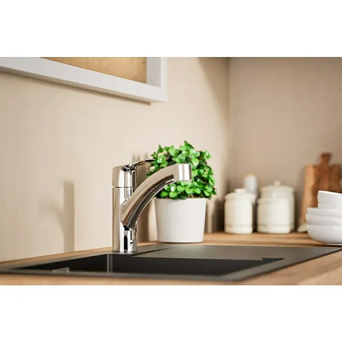 Grohe QuickFix Spültischarmatur Start - Chrom, Ausziehbar, Glänzend - Nahaufnahme einer modernen Spültischarmatur aus Chrom in einer Küche mit Pflanze und Behältern im Hintergrund.