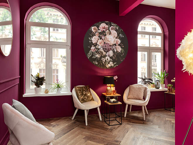 2 Stühle in weiß neben Beistelltischen, die Wände in Magenta gestrichen und mit einer Blumen-Fototapete verziert