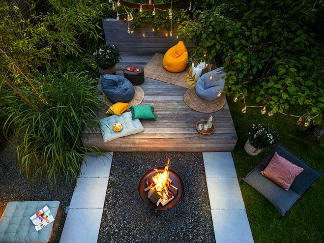 Feuerstelle bei Nacht im Garten mit Sitzecke und Beleuchtung