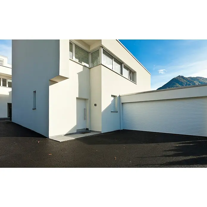 E2 elektro LED-Außenwandleuchte Mago - 11 W, 15 x 15 x 4 cm, Anthrazit, IP54 - Außenansicht eines modernen, weißen Hauses mit Garagentor, Fenstern und dunkler Auffahrt. Klare Linien und minimalistisches Design.