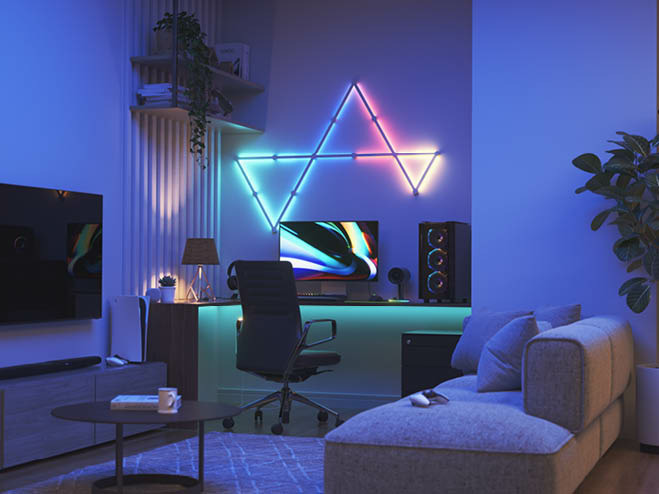 Im Wohnzimmer eine kleine Nische mit Schreibtisch und Computer, and er Wand ein LED-Paneel in mehreren Farben