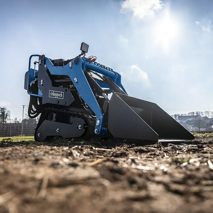 Scheppach Kompaktlader MKL730 - Benzin, Traglast: 200 kg, Tankvolumen: 6 l - Nahaufnahme eines Scheppach Miniladers auf einem Feld, der für Bau- und Gartenarbeiten konzipiert wurde.