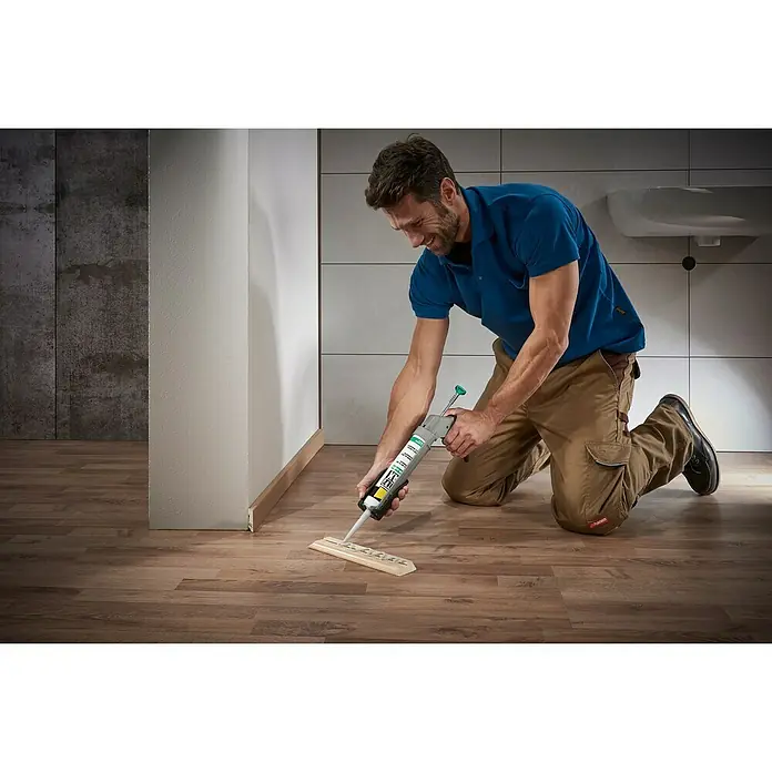 Wolfcraft Kartuschenpresse MG 211 ERGO - Passend für: 310 ml Kartuschen Ø 50 x 225 mm, Acryl - Mann kniet und verwendet eine Kartuschenpistole, um Klebstoff auf ein Holzstück aufzutragen, wahrscheinlich zur Montage.